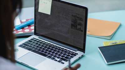Estudante com laptop e cadernos, focado nos estudos
