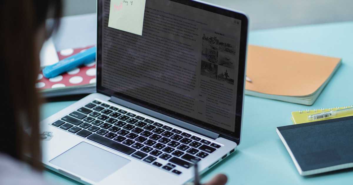 Estudante com laptop e cadernos, focado nos estudos