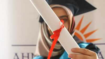 Mulher em beca de formatura segurando diploma, celebrando conquista acadêmica