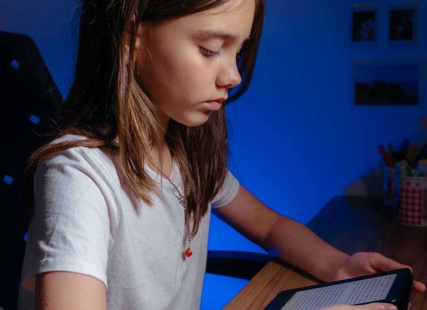Jovem lendo em tablet numa mesa, ambiente aconchegante de estudo