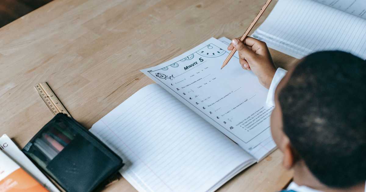 Estudante escrevendo em caderno durante atividade escolar