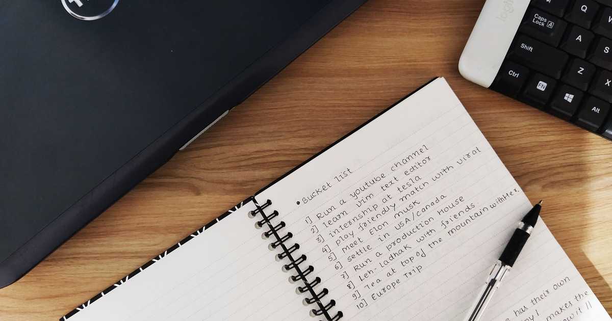 Espaço de trabalho com laptop, caderno e teclado sobre mesa de madeira