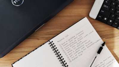 Espaço de trabalho com laptop, caderno e teclado sobre mesa de madeira