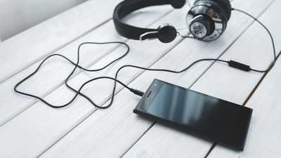 Smartphone conectado a fones de ouvido sobre uma mesa de madeira