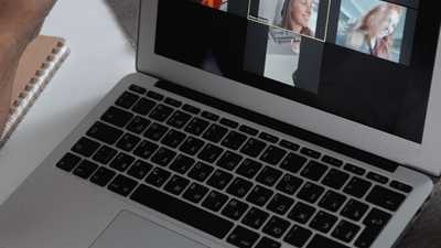 Mãos em laptop mostrando videochamada em grupo em ambiente de home office