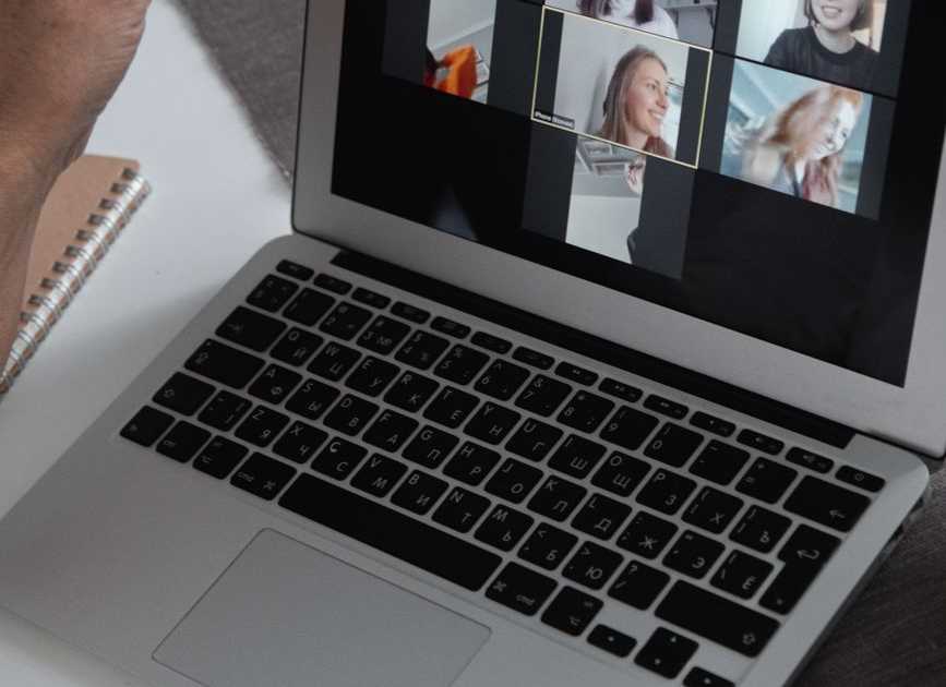 Mãos em laptop mostrando videochamada em grupo em ambiente de home office
