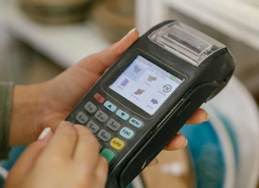 Mãos operando uma maquininha de cartão em um ambiente de varejo